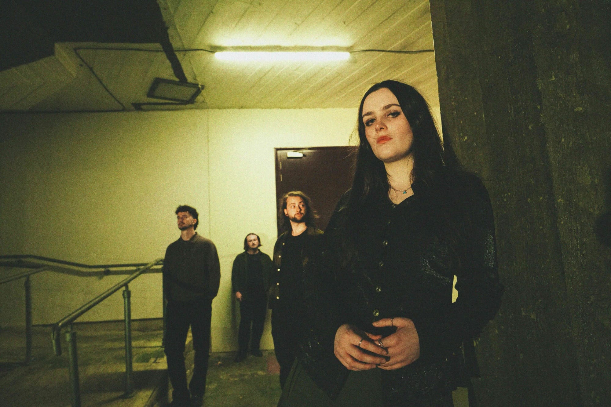 Singer Cait Whitley with Slaney Bay in a dimly lit stair case