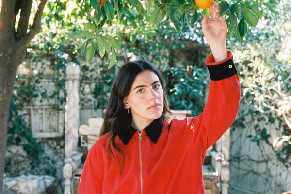 Avery Lynch in a red jacket beneath an orange tree