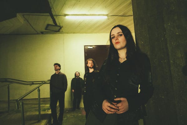 Singer Cait Whitley with Slaney Bay in a dimly lit stair case